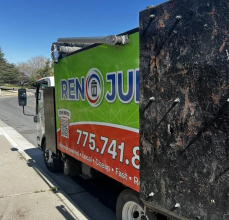 Truck loaded with junk haul container labeled "Reno Junk Removal"